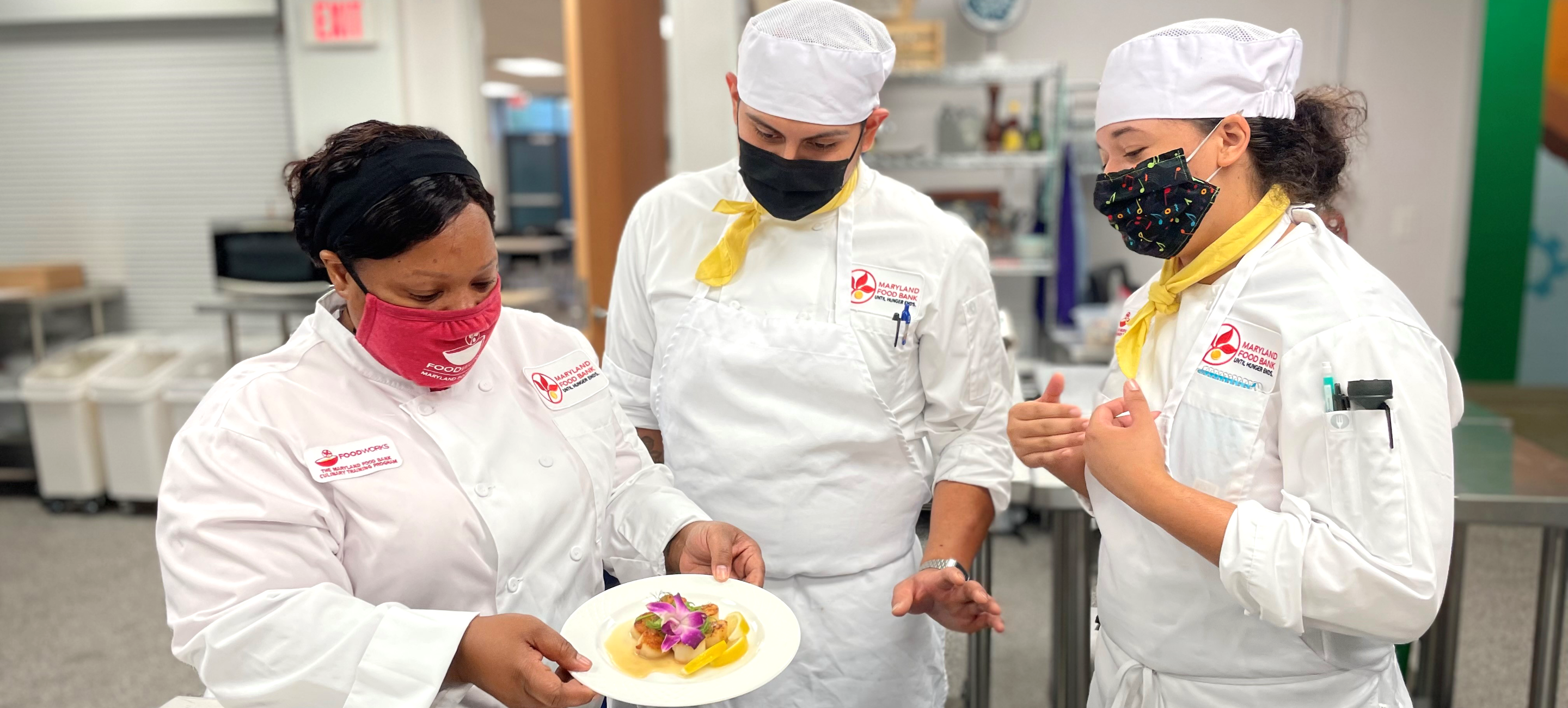 Chef Moe teaches two FoodWorks students plating techniques