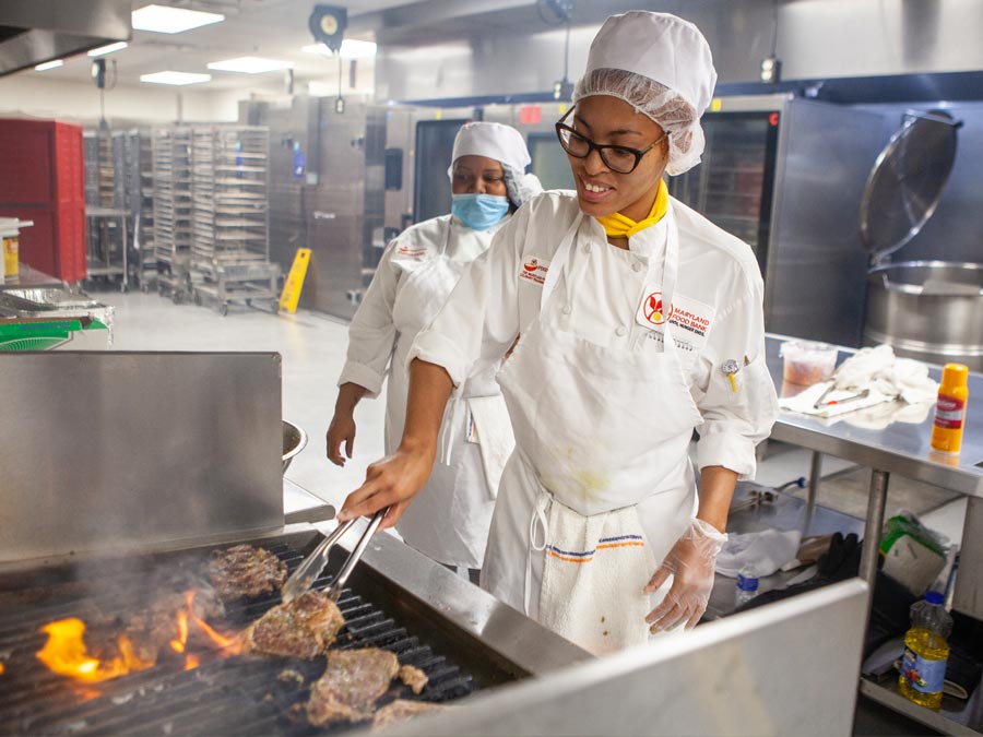 two black female chefs cooking flaming steaks