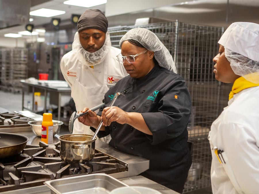 Chef Moe trains two FoodWorks students at the stove