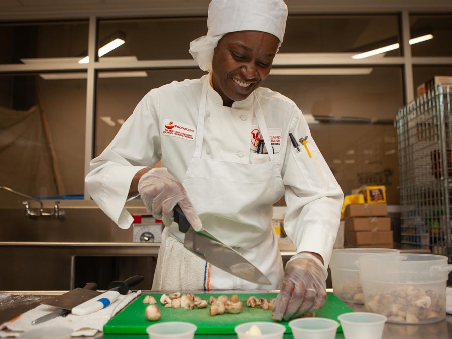 smiling black FoodWorks student chopping mushrooms